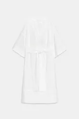 Vestido tipo túnica de corte evasé, color blanco, con escote en pico, mangas por debajo del codo y cinturón ajustable del mismo tejido.