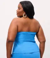 Blusa strapless de viscolino, con diseño de escote recto y recortes frontales que le otorgan una estructura entallada. Presenta un ruedo ligeramente abierto y cierre lateral mediante cremallera.