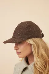 Gorra con visera confeccionada en lana fina sin teñir, con un sutil patrón de tejido en espiga.