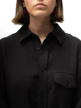 Camisa unisex de lino con mangas tres cuartos, cuello clásico, cierre frontal con botones y un bolsillo aplicado en el pecho.