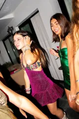 Vestido corto negro con estampado de plumas doradas, escote en V, breteles finos cruzados en la espalda, cut-outs laterales y volado en el ruedo.