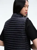 Chaleco acolchado de Save The Duck, con diseño de estructura horizontal, cuello alto y cierre frontal con botones a presión. Confeccionado en nylon ultraligero con relleno tecnológico que proporciona aislamiento térmico y protección contra el viento.