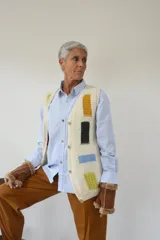 Chaleco tejido a mano en lana merino, con escote en V, cierre frontal de botones de madera y diseño con detalles geométricos de colores.