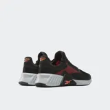 Championes de entrenamiento Reebok Flip Charge, color negro con detalles en naranja coral. Presentan una malla transpirable en la parte superior, refuerzos laterales y una entresuela robusta en gris claro con el logo de Reebok en naranja en la parte trasera.