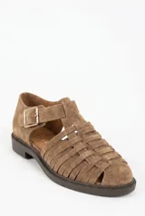 Sandalias cangrejeras de gamuza color visón, con diseño tejido de tiras cruzadas, puntera redondeada, suela plana y tira ajustable con hebilla metálica en el tobillo.