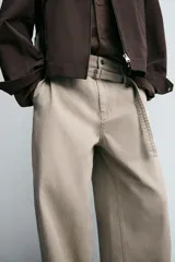Pantalón de algodón color beige, estilo wide balloon fit, con cintura ajustable mediante cinturón de la misma tela. Presenta bolsillos frontales y bolsillos traseros de plastrón, con efecto lavado y abertura en el bajo.