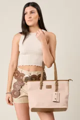 Cartera tote color rosa pálido de ecocuero texturado con detalles en tono camel. Tiene doble asa de hombro, logo de la marca grabado en el frente, llavero colgante y múltiples compartimentos interiores.