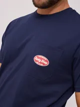 Remera color crema de manga corta con cuello redondo y bolsillo en el pecho con logo estampado de Rusty Shop Surf Services.