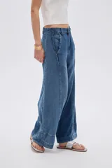 Pantalón jean azul de tiro alto, corte baggy y piernas anchas, con costuras decorativas frontales.
