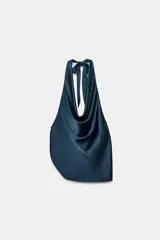 Top de tejido satinado con cuello halter, lazada posterior y escote drapeado, con diseño asimétrico en el ruedo.