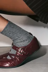 Bailarinas color bordó con efecto acharolado, detalle de pespuntes, cierre de hebilla metálica ajustable y tiras elásticas cruzadas en la parte frontal. Acabado en punta redonda y suela de 0,5 cm.