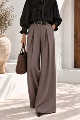 Pantalón de vestir gris topo, de corte ancho y relajado, con pinzas frontales, trabillas para cinto y bolsillos laterales.