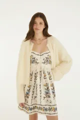 Cardigan básico de punto color marfil, con textura suave y esponjosa, cierre frontal de botones y mangas largas holgadas.