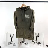 Canguro verde oliva con efecto lavado, corte oversize, capucha con cordón ajustable y bolsillo tipo canguro. Estampado frontal con texto en blanco "Water under the bridge" y logo de la marca Duxon.