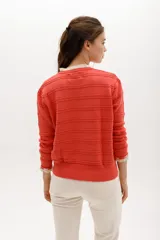 Sweater de punto negro con detalle de calados y lazo en el escote. Tiene ribetes con volados en contraste en el cuello y puños.