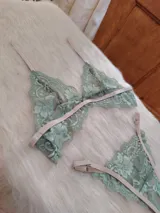 Conjunto de lencería compuesto por un bralette triangular y una bombacha tipo tanga, confeccionados en encaje color verde oliva con detalles y elásticos en tono tostado.