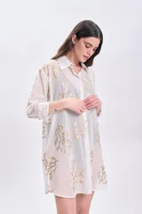 Camisa blanca de algodón con estampado de ramas doradas, de corte recto y mangas largas.