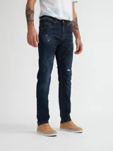 Jean de calce slim fit, color azul oscuro con detalles de desgaste y roturas.