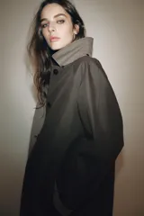 Trench reversible de corte recto con cuello de solapa y aplicación de pelo sintético extraíble. Presenta cierre frontal con botones, manga larga y bolsillos laterales ocultos en las costuras.
