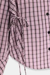 Camisa de manga larga con estampado de cuadros en tonos rosados y negros. Presenta cuello solapa, bolsillo delantero de plastrón, cierre frontal con botones y detalle de laterales ajustables con lazos.