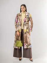 Trench de diseño urbano con acabado agamuzado, de corte recto y largo midi. Presenta un estampado abstracto multicolor con tonos rojizos, azules y ocres, cuello solapa, mangas largas y cinturón ajustable en la cintura.