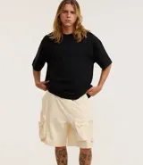 Bermuda masculina de poliéster color negro, corte baggy cropped, con cintura elástica ajustable con cordón y bolsillos funcionales.