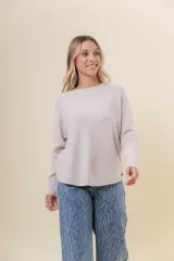 Buzo tejido de punto en color beige, con cuello redondo, mangas largas y silueta relajada con dobladillo irregular, siendo más largo en la parte trasera.