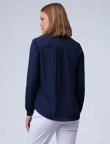 Blusa azul marino de gasa marca Zac & Rachel, con cuello a la base y escote en V. Manga larga regulable con presilla y botón. Aplique de puntilla en hombros.