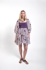 Vestido corto de encaje morado y crudo, con cuerpo superior fruncido y elastizado, escote recto, mangas abullonadas y falda corta con volados.