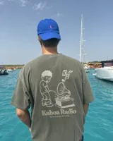 Remera oversize negra con diseño gráfico en la espalda que incluye la inscripción "Kaboa Radio" y un personaje ilustrado, de corte amplio y mangas cortas.