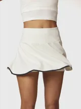 Falda skort deportiva de tiro alto, color blanco con borde inferior en contraste negro. Incluye short integrado con bolsillo lateral.