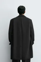 Abrigo de corte regular fit confeccionado en tejido compacto con mezcla de lana. Presenta cuello con solapas de muesca, cierre frontal de botonadura, bolsillos de vivo en la cadera y abertura central en la espalda.