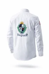 Camisa de manga larga color blanco, con cuello clásico y puños abotonados. Presenta un gran bordado en la espalda que incluye el escudo nacional y el logo de la marca Bagual.