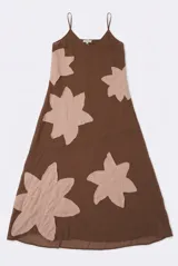 Vestido largo marrón de gasa con tirantes finos, escote en V y grandes parches decorativos en forma de flor en tonos rosados.