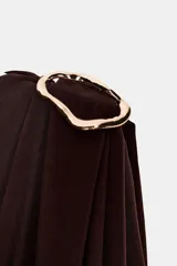 Body de manga larga color marrón oscuro, con escote asimétrico drapeado y detalle de broche metálico en el hombro derecho.