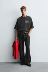 Camiseta negra con efecto lavado, corte boxy fit, cuello redondo y manga corta. Presenta un estampado frontal con texto en tonos turquesa, rojo y blanco que dice "Tuesday 600 Marathon Day Hyde Park".