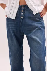 Pantalón de jean de tiro bajo y calce relajado, con cierre frontal de múltiples botones visibles y largo al tobillo.