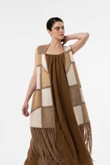 Chaleco largo de inspiración boho, confeccionado en paneles de gamuza combinados en tonos neutros con costuras artesanales y flecos XL en el ruedo.