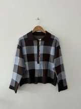 Sweater de tejido bremer con diseño de cuadros grandes en tonos marrón y celeste, cuello tipo polo con cierre frontal de botones y mangas largas.