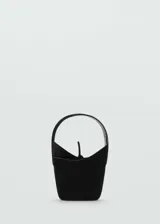 Bolso de mano tipo bucket en color negro, confeccionado en piel con acabado aterciopelado. Presenta un diseño minimalista con asa superior integrada y cierre mediante lazo ajustable en la parte central.