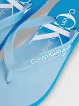 Ojotas de playa con suela y tiras en degradado de azul claro a celeste, con el logo de Calvin Klein Jeans estampado en blanco en la plantilla y en la tira.