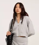 Saco gris de corte slim, confeccionado en algodón y viscosa certificada, con capucha y cordón ajustable, cierre frontal con cremallera y forro de fleece.