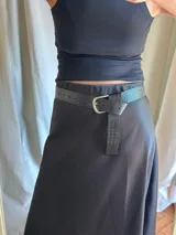 Cinturón negro con hebilla plateada y textura símil piel de cocodrilo.