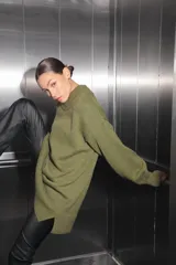 Sweater verde oliva de tejido de punto con cuello polo, mangas largas y corte oversize. Presenta un parche con monograma en la espalda.