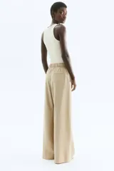 Pantalón color beige de corte amplio, con cintura elástica y lazo para atar. Confeccionado en sarga de mezcla de modal, con bolsillos laterales y un bolsillo decorativo atrás.