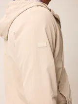 Campera de nylon con cierre frontal, capucha ajustable con cordones y forro interior a cuadros. Presenta bolsillos laterales y logo bordado en el pecho.