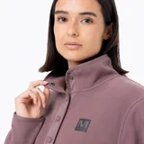 Buzo polar de microfleece color rosa viejo, con cuello alto, cierre frontal parcial con botones a presión y bolsillo frontal tipo canguro. Presenta detalles en nylon en la tapeta y los bolsillos, y puños con sujeción elástica.