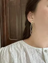 Aros colgantes dorados con forma de ramas onduladas.