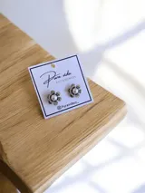 Aros tipo caravana con diseño de flor de metal plateado y centro de perla blanca.
