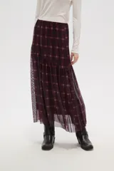 Falda larga de corte evasé con estampado de cuadros escoceses en tonos bordó y negro. Presenta un diseño de doble capa con una base opaca y una sobrecapa de tul semitransparente, con un corte asimétrico en la parte inferior.
